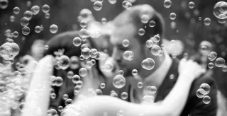 Wedding couple kissing among soap bubbles